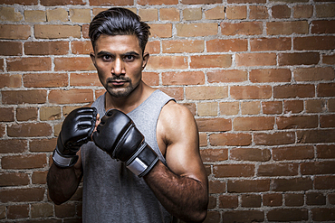 Portrait of man with boxing gloves against brick wall