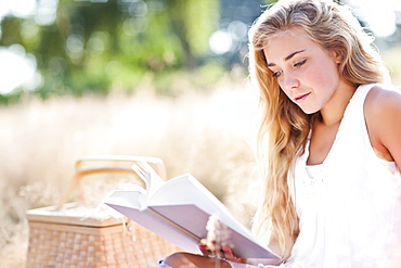 Teenage girl (16-17) reading book outdoors