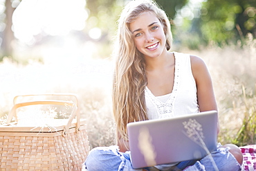 Teenage girl (16-17) posing with laptop outdoors