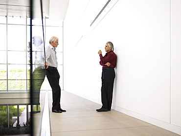 Two businessmen meeting in modern office hallway