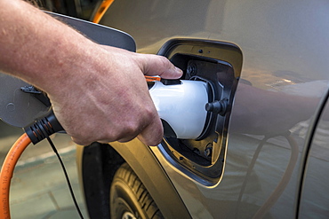 Mans hand holding charge cable in electric vehicle