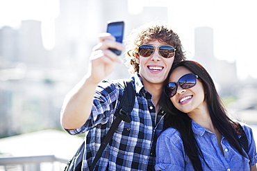 USA, Washington, Seattle, Couple wearing sunglasses photographing themselves with smart phone