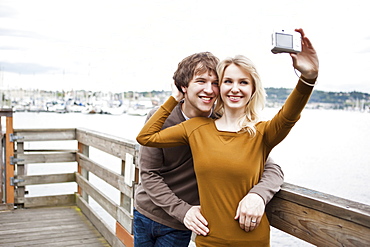 USA, Washington, Seattle, Young couple taking photos on pier