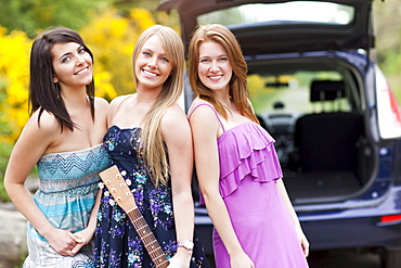 Portrait of young women with guitar by car