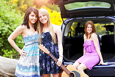 Portrait of young women with guitar by car