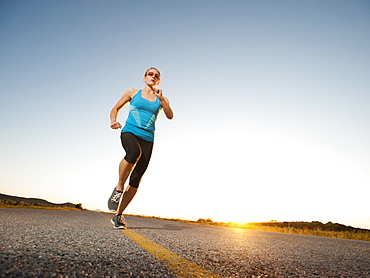 Mid adult couple running on empty road