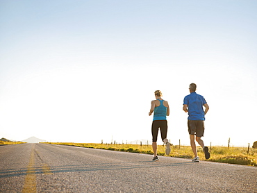 Mid adult couple running on empty road