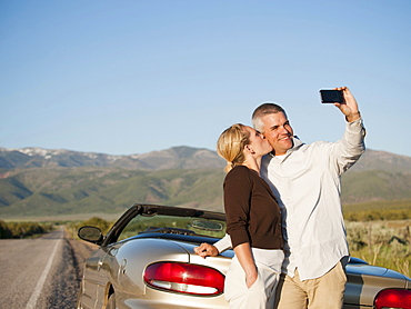 USA, Utah, Kanosh, Mid adult couple photographing themselves in front of majestic mountain range