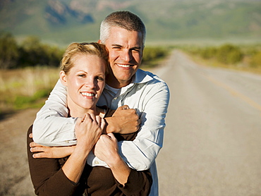 Mid adult couple embracing on empty road