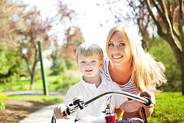 Mother and son (2-3) riding tricycle in park