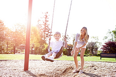 USA, Washington State, Seattle, Mother and son (2-3) swinging on swing in park