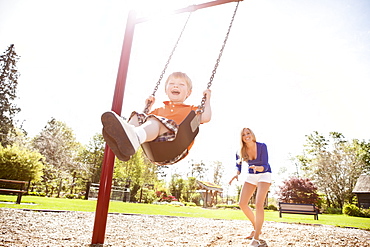 USA, Washington State, Seattle, Mother and son (2-3) swinging on swing in park