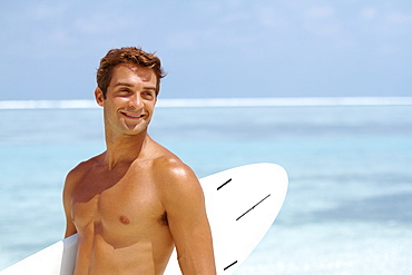Shirtless young man holding surfboard