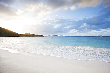 Sea waves on sandy beach and clouds at sunset