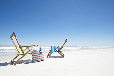 Two deck chairs, beach bag and beach towel on beach