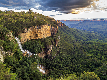 Waterfall and forested rocky mountains