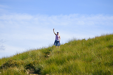 Woman in sunglasses standing on grassy field and waving