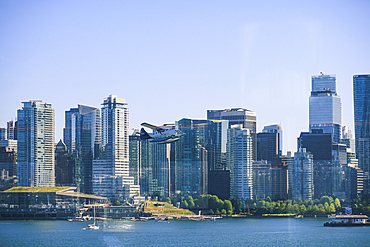 Seaplane flying above Burrard Inlet, downtown buildings in background