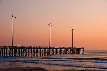 USA, North Carolina, Outer Banks, Kill Devil Hills, pier with wind turbines at sunset