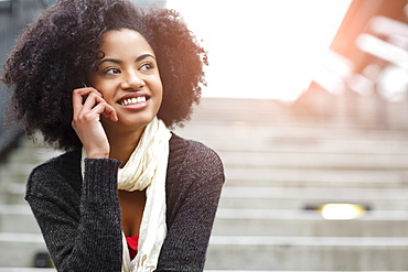 USA, Washington State, Seattle, young woman sitting on steps and talking on mobile phone