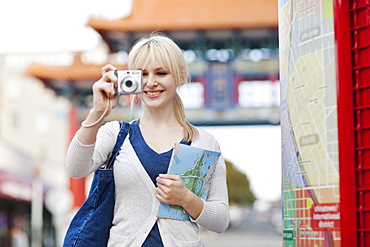 USA, Seattle, Young woman taking photos and holding map