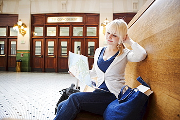 USA, Seattle, Young woman sitting at train station and reading map