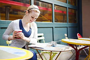 USA, Seattle, Young woman sitting with coffee and reading map