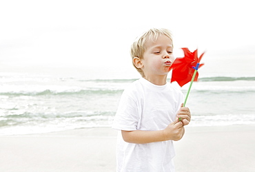 Boy (4-5) blowing on red pinwheel