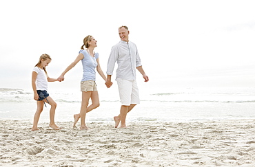 Girl (10-11) walking on beach with parents