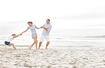 Girl (10-11) playing on beach with parents