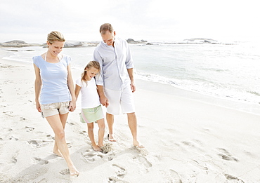 Girl (10-11) playing on beach with parents