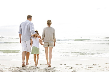 Girl (10-11) playing on beach with parents