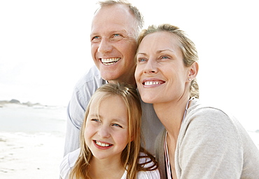 Girl (10-11) playing on beach with parents