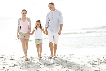 Girl (10-11) playing on beach with parents