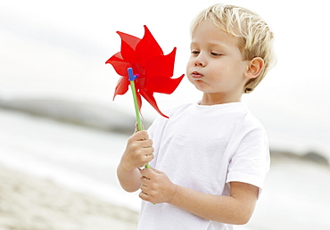 Portrait of boy (4-5) playing with pinwheel on beach