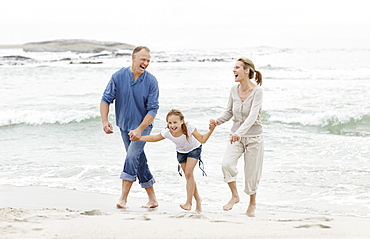 Girl (10-11) playing on beach with parents