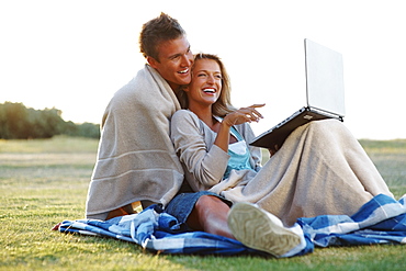 Couple looking at laptop outdoors