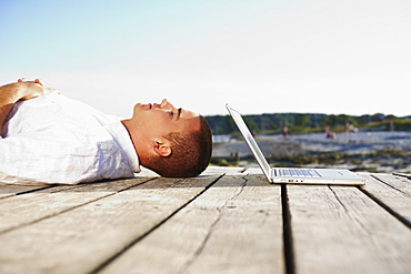 Man sleeping next to laptop on dock