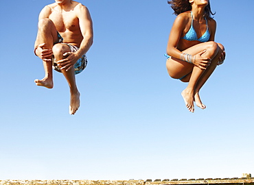 Young couple jumping of dock