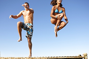 Young couple jumping of dock