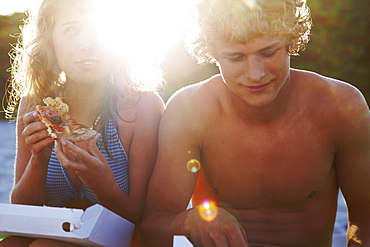 Young couple eating pizza on beach