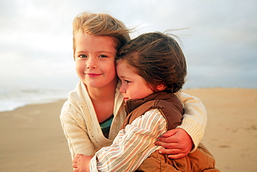 Sister and brother hugging at beach