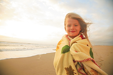 Girl wrapped in blanket at beach