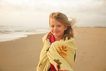 Girl wrapped in blanket at beach