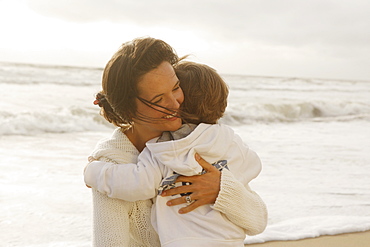 Mother hugging child at beach