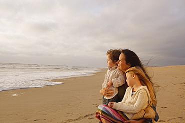 Mother hugging children at beach