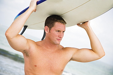 Bare-chested man holding surfboard