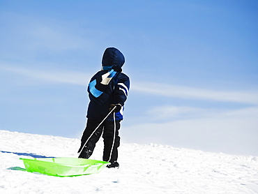 Child pulling sled in snow