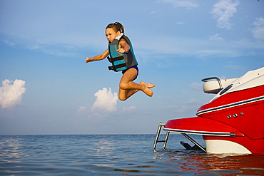 Girl in lifejacket jumping off boat, Florida, United States