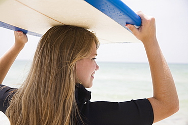 Girl holding surfboard on head, Florida, United States